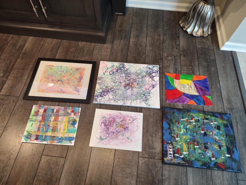 Puede incluir: Seis pinturas abstractas en varios colores y estilos, incluyendo una pintura enmarcada con un dise&ntilde;o rosa y verde, una pintura con un dise&ntilde;o azul y verde y una pintura con un dise&ntilde;o rojo, amarillo y morado.