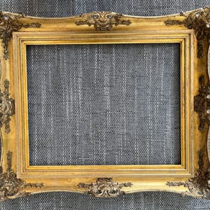 Könnte beinhalten: Verzierter, rechteckiger goldener Bilderrahmen mit detaillierten Schnörkeln und Verzierungen. Der Rahmen hat eine antike Oberfläche, die ihm ein Vintage-Aussehen verleiht. Der Innenraum ist leer, bereit für ein Foto oder Kunstwerk. Der Rahmen ist ein dekoratives Stück.