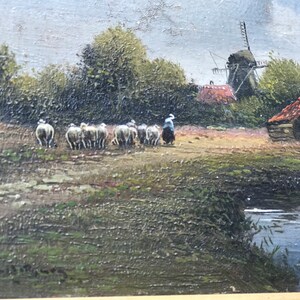 Op de afbeelding: Een schilderij van een landelijk landschap met een windmolen, een boerderij en een herder die een kudde schapen over een pad leidt. De sc&egrave;ne is geschilderd in gedempte tinten bruin, groen en blauw, met een vleugje oranje in het dak van de boerderij.