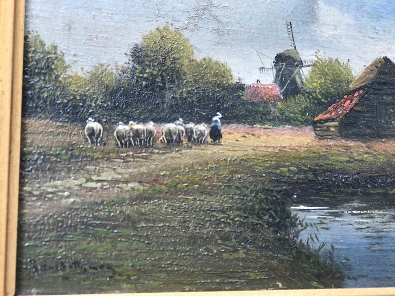 Op de afbeelding: Een schilderij van een landelijk landschap met een windmolen, een boerderij en een herder die een kudde schapen over een pad leidt. De sc&egrave;ne is geschilderd in gedempte tinten bruin, groen en blauw, met een vleugje oranje in het dak van de boerderij.