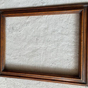 Può includere: Una cornice rettangolare realizzata in legno marrone scuro con una venatura naturale visibile. La cornice presenta un design a profilo a gradini su più livelli con bordi netti e precisi e una finitura liscia e lucida su tutta la struttura.