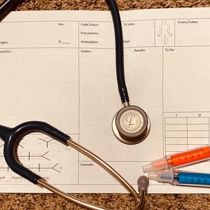 May include: A medical chart with a stethoscope, a blood pressure cuff, and three syringes. The chart has sections for allergies, hospitalist, diagnosis, and other medical information.