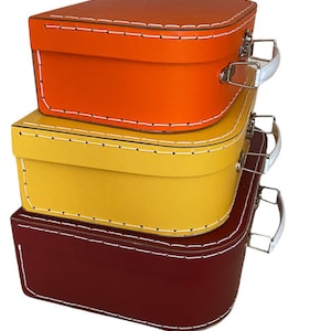May include: Three stackable storage boxes with white stitching and handles. The top box is orange, the middle box is yellow, and the bottom box is burgundy.