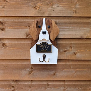May include: Wooden dog-shaped key holder with two hooks. The dog is brown and white with black eyes and a black nose. The sign says "Milo's Lead".