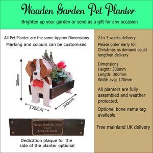 May include: Wooden pet planter shaped like a dog with a brown and white painted design. The planter is 12 inches tall, 12 inches long, and 7 inches wide. The planter has a black wooden base and a bone-shaped name tag. The planter is shown with a small plant inside. The text "Happy Birthday Nan! Love James & Paula" is on a black plaque.