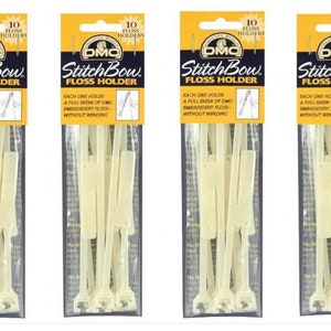 May include: Four packages of DMC Stitch Bow Floss Holders. Each package has a yellow header with the text "10 Floss Holders" and the DMC logo. The holders are a light cream color and are designed to hold embroidery floss.