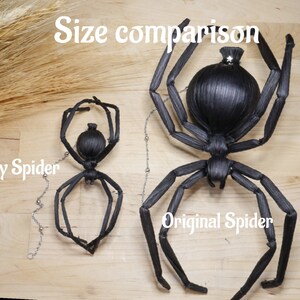May include: Size comparison of two black spider sculptures. The larger spider is labeled "Original Spider" and the smaller spider is labeled "Baby Spider".