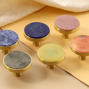 May include: A set of three ceramic mugs with a speckled, matte finish in cream, light grey, and dark grey. Each mug has a simple, minimalist design, suitable for coffee or tea.