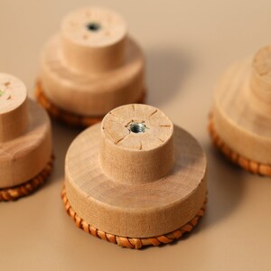 May include: Five wooden knobs with a woven rattan base. The knobs are light brown and have a small metal screw in the center.