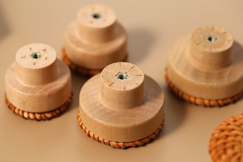 May include: Five wooden knobs with a woven rattan base. The knobs are light brown and have a small metal screw in the center.