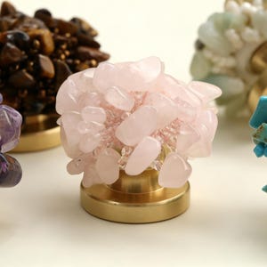 Peut inclure: Gros plan de plusieurs bouchons de bouteille décoratifs. Chaque bouchon présente un amas de pierres précieuses colorées, dont l'améthyste, l'œil de tigre, le quartz rose, la turquoise et le jade, monté sur une base dorée.