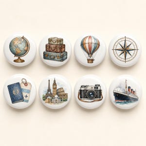 Könnte beinhalten: Ein Set aus acht runden, weißen Keramikknöpfen mit Reise-Illustrationen, darunter ein Globus, gestapelte Vintage-Koffer, ein Heißluftballon, eine Kompassrose, ein Reisepass mit Anhänger, berühmte Bauwerke, eine Kamera und ein Kreuzfahrtschiff.