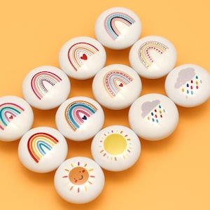 May include: A set of 10 white ceramic knobs with colorful rainbow, sun, and cloud designs. The knobs are perfect for adding a touch of whimsy to any room.