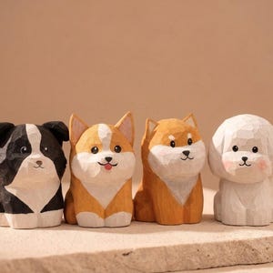 Könnte beinhalten: Vier kleine, handgeschnitzte Hunde-Figuren aus Holz, die in einer Reihe stehen. Die erste ist schwarz-weiß, die zweite ist hellbraun-weiß mit einer kleinen Zunge, die dritte ist hellbraun-weiß und die vierte ist weiß mit rosa Wangen.