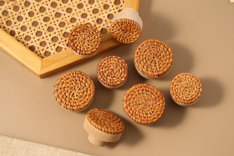 May include: Eight round woven rattan knobs in natural brown tones. The knobs have a slightly raised center and are perfect for adding a touch of rustic charm to furniture.