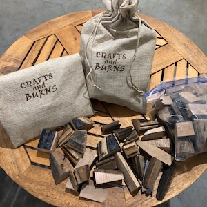 May include: Two burlap bags with the text "Crafts and Burns" printed on them. The bags are filled with wood chips for smoking meat. The wood chips are in a clear plastic bag.