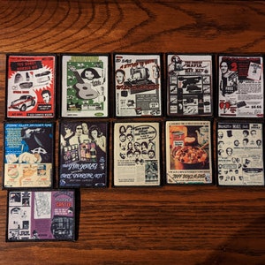 May include: A collection of rectangular patches with various vintage-style graphics and text. The patches feature images of a guitar, a car, and text that reads "TED BONDY MORDER KIT", "THE JIM JONES CULT PARLOR KIT", and "MURDER CASTLE".