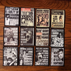 May include: A collection of black and white patches resembling vintage newspaper headlines. The patches feature various sensationalized news stories with bold headlines and images, including topics like Satan, Elvis, and Bigfoot.