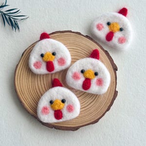 May include: Four white needle-felted chicken ornaments with red combs, yellow beaks, and pink cheeks. Each chicken has small black bead eyes. The ornaments are arranged on a round wooden slice with visible growth rings, featuring a natural texture.