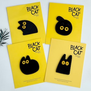 Peut inclure: Quatre cartes jaunes avec des écussons brodés de chats noirs aux yeux jaunes. Les cartes portent l'inscription "BLACK CAT EMBROIDERY PATCH" et la phrase "I hope that the world will become more beautiful because of you."