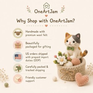 May include: A needle-felted calico cat figurine with a green bow tie sits in a small, round, crocheted basket adorned with felt flowers and a heart. The image includes the text OneArtJam and a list of shop features including handmade wool felt, gift packaging, US shipping, tracked delivery, and customer support.