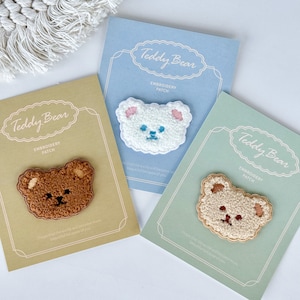 May include: Three embroidered teddy bear patches on card stock. The patches are brown, white and beige. The text on the cards reads "Teddy Bear Embroidery Patch".