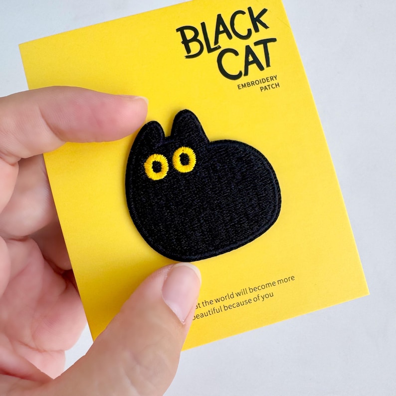 May include: Black cat embroidery patch with yellow eyes on a yellow card. The card reads "BLACK CAT" and "EMBROIDERY PATCH". The patch is a cute, cartoon-style design.