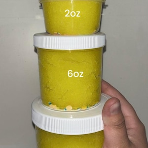 May include: Three clear plastic jars filled with bright yellow slime, stacked vertically. Each jar has a white lid and a label indicating its volume: 2oz, 6oz, and 8oz. Text at the top reads: This is for size reference only. You will receive the slime you ordered.