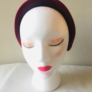 May include: A wide, burgundy velvet headband for women. The headband is made of soft, plush velvet and is designed to be comfortable to wear.