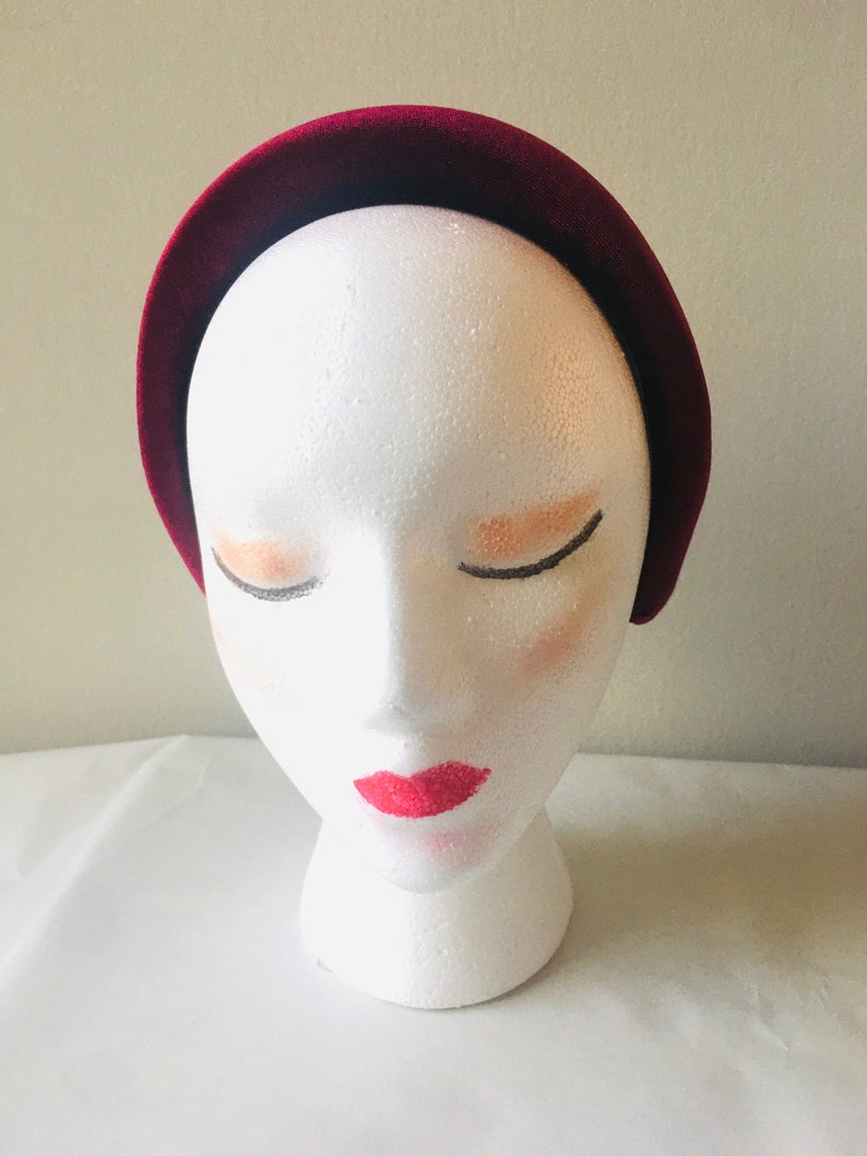 May include: A wide, burgundy velvet headband for women. The headband is made of soft, plush velvet and is designed to be comfortable to wear.