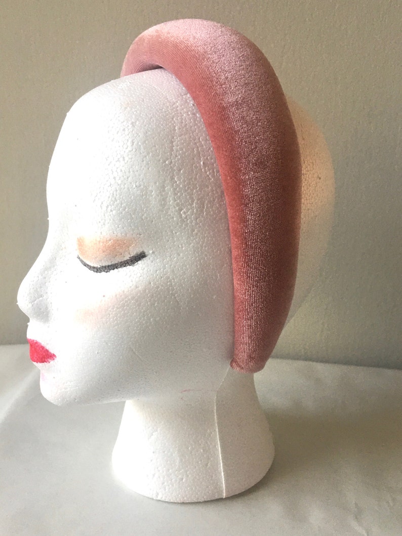 May include: A wide, blush pink velvet headband. The headband is thick and has a smooth, soft texture.
