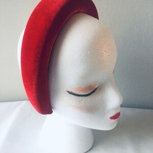 May include: A wide red velvet headband for women. The headband is thick and has a curved shape.