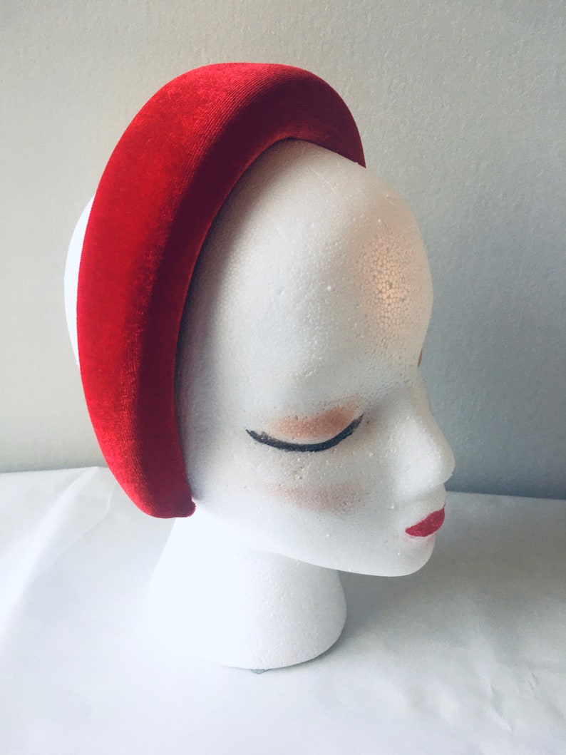 May include: A wide red velvet headband for women. The headband is thick and has a curved shape.