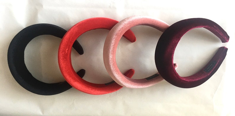 May include: Four velvet headbands in different colors: black, red, pink, and burgundy. The headbands are all the same size and shape, and they are arranged in a row.
