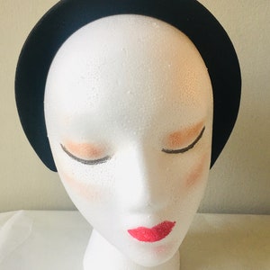 May include: A black velvet headband on a white mannequin head.