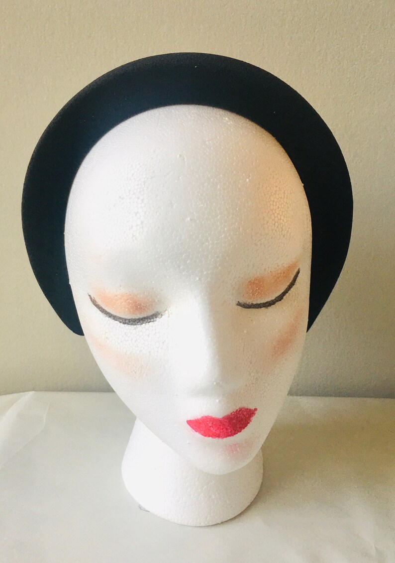 May include: A black velvet headband on a white mannequin head.