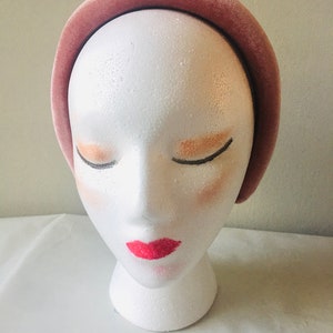 May include: A wide, dusty rose velvet headband. The headband is shown on a white mannequin head.