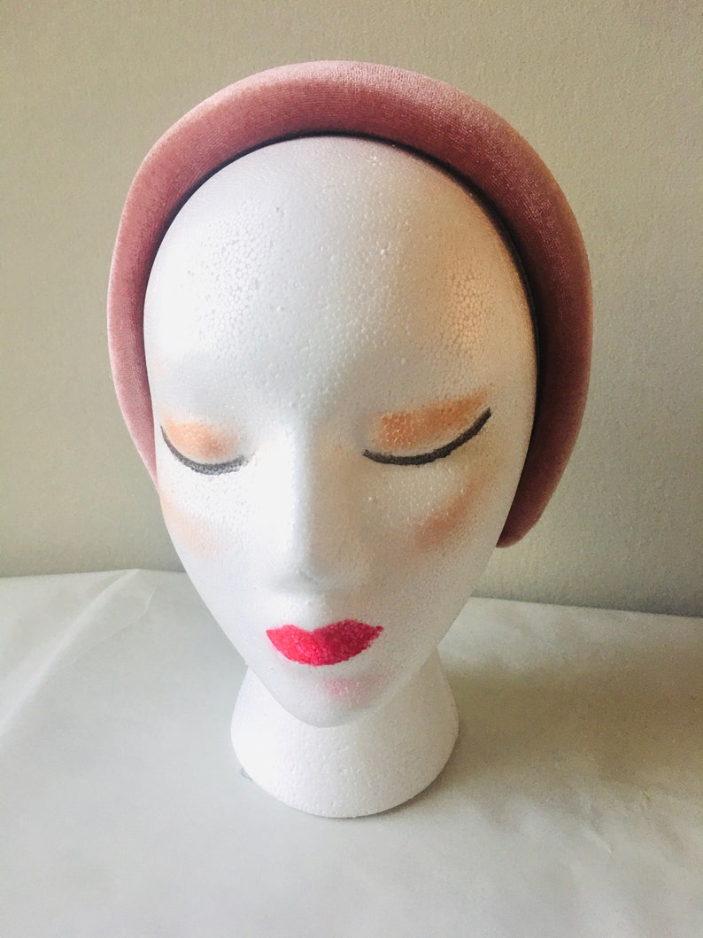 May include: A wide, dusty rose velvet headband. The headband is shown on a white mannequin head.