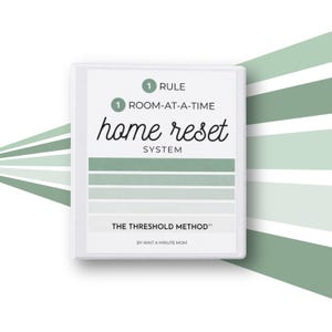 May include: A white book cover with the title "home reset SYSTEM" in black script. The cover also includes the text "1 RULE" and "1 ROOM-AT-A-TIME". Below the title are horizontal green stripes. The text "THE THRESHOLD METHOD" and "BY WAIT A MINUTE MOM" are also present.