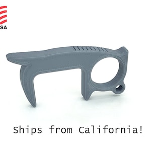 Puede incluir: Un abridor de puertas de plástico gris con un asa de bucle. La herramienta está diseñada para ayudar a las personas a evitar tocar las superficies en lugares públicos.