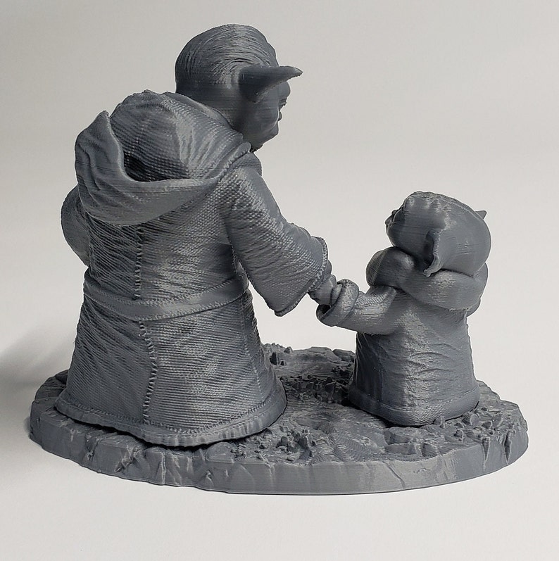 Peut inclure: Une figurine en 3D imprim&eacute;e en gris de Yoda et un Yoda plus petit, debout c&ocirc;te &agrave; c&ocirc;te sur une base grise. Le grand Yoda porte une robe et a une expression s&eacute;rieuse. Le petit Yoda regarde le grand Yoda.