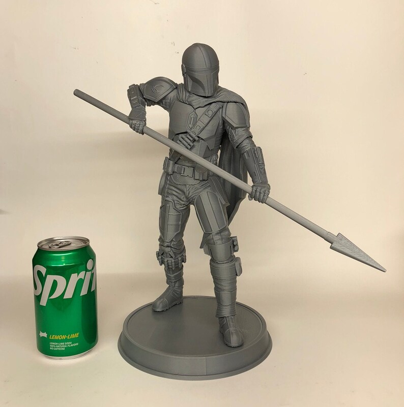 Puede incluir: Una figura de acci&oacute;n gris impresa en 3D de un personaje de la franquicia Star Wars, sosteniendo una lanza. La figura est&aacute; de pie sobre una base redonda.