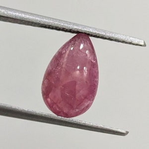 May include: A teardrop-shaped pink gemstone with a smooth, polished surface.