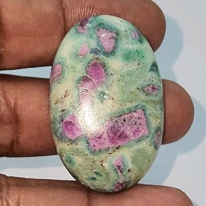 May include: Oval shaped green and pink gemstone with a swirling pattern.