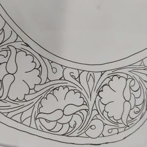 Könnte beinhalten: Eine Schwarzweiß-Zeichnung eines floralen Designs. Das Design zeigt eine sichelförmige Form mit filigranen Details aus Blättern und Blüten.