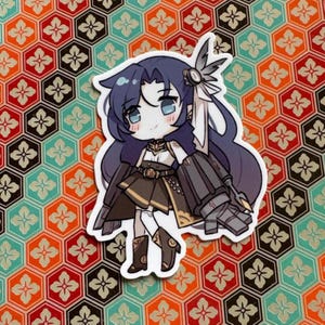 May include: A die-cut sticker of a chibi anime character with blue hair and eyes, in a dark outfit with gold details. The sticker is set against a patterned background with red, orange, and teal geometric shapes.