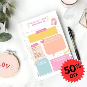 May include: A notepad for daily fertility cycle check-ins, featuring sections for mood, checklist, and self-care. The text "The Fertility Cycle" and "Daily Check-In" are displayed. A cross-stitch hoop with the word "LOVE" is also visible.