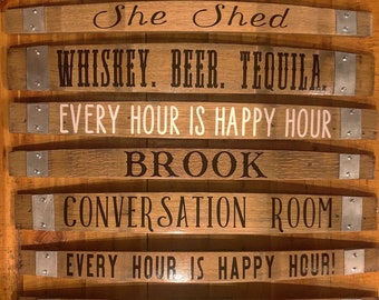 May include: A set of six wooden barrel signs with metal accents. The signs are decorated with black lettering and feature phrases like "She Shed", "Whiskey. Beer. Tequila", "Every Hour is Happy Hour", and "Lonas Bros."