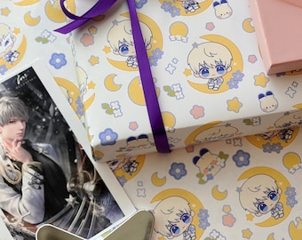 May include: A white gift wrap with a repeating pattern of a cartoon character with blonde hair, a blue shirt, and a crescent moon. The character is repeated on a white background with small blue flowers, yellow stars, and white dots. A purple ribbon is tied around the gift wrap.