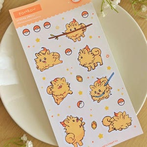 May include: A sticker sheet with cartoon illustrations of a fluffy, orange creature with flames on its head. The sheet includes the word "POMBON" and the text "STICKER SHEETS" in orange, along with the artist's name. The stickers are on a white background.